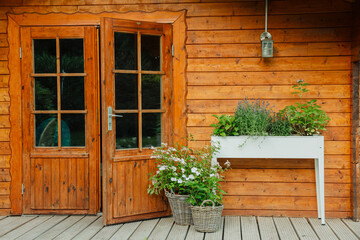 Raised bed with plants and flowers next to a wooden house in the garden. Hydrangea and lavender in...