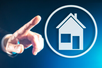 House logo on a virtual screen. Hand reaches for house sign. Real estate business concept. Metaphor of digital architecture. Digital activity with real estate. Selling real estate on Internet