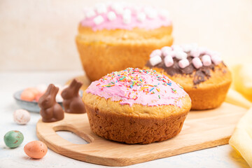 Homemade glazed and decorated easter pies with chocolate eggs and rabbits on a white concrete background. Side view, selective focus.