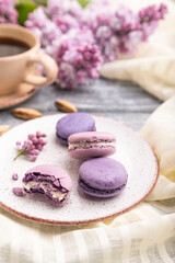 Purple macarons or macaroons cakes with cup of coffee on a gray wooden background. Side view, selective focus.