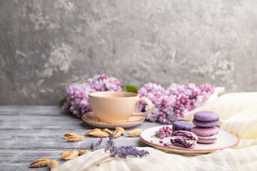 Fototapeta na wymiar Purple macarons or macaroons cakes with cup of coffee on a gray wooden background. Side view, copy space.