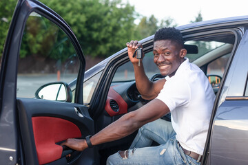 A happy African-American man holds the car keys. Car sales and rentals
