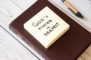 God's timing is perfect. God Jesus Christ is always on time. Trust, have faith and hope, belief in God's Word and promises. Inspiring Holy Bible quote with notes and pen on wooden background. 
