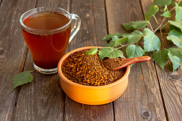 A cup of chaga tea on a dark table. Chaga slices and birch twig