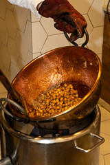 Mujer con cacerola de cobre haciendo almendras fritas con caramelo.