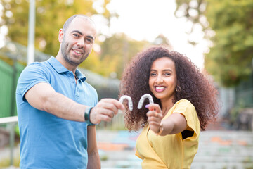 Happy and smiling couple from different races are holding an invisaligner. Includes copy and text space.