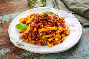 Traditional casarecce al bronzo al rag italian pasta with minced meat tomato ragu sauce served as close-up on a design