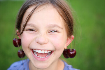 Pretty little girl with cherry earrings on green background.