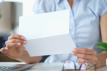 Woman reading letter while sitting at table with open envelope - obrazy, fototapety, plakaty