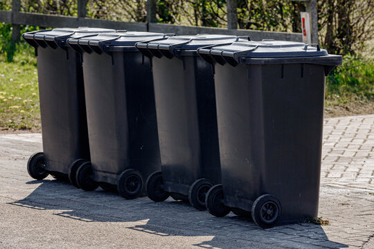Waste separation, Four different black trash can standing in front of the house in public along street waiting for the officer to collect, Help to reduce waste, Help global warming.