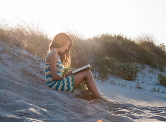 Joven mujer leyendo un libro junto al mar. Concepto de lectura, relajación y tiempo libre.