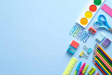 Back to school background with school supplies on blue desk. Flat lay, top view, ovehread.