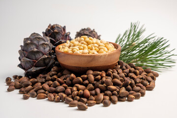Pine nuts in wooden bowl with cones on white background