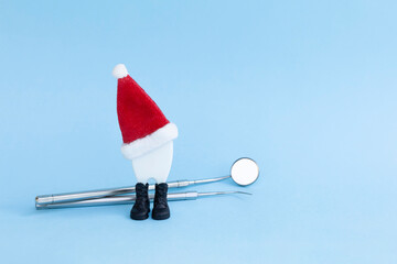 dental tools and New Year tooth in santa hat. mirror, probe for examining mouth. treatment, prevention, oral hygiene. Christmas gift, medical treatment discount. copy space, text - obrazy, fototapety, plakaty