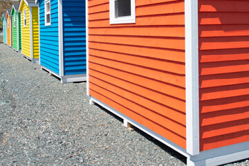 The corner of a bright orange wooden clapboard exterior wall of a shed. The narrow trim is white...