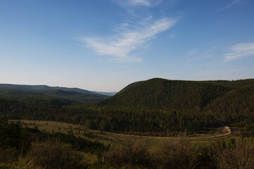 This is a dirt road in the mountains. There is a view from a high point in the mountains.