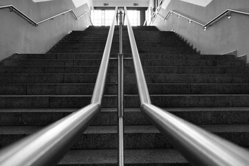 Grayscale closeup shot of metal tubes leading upward on a staircase in a subway