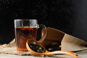 A glass mug of fragrant brewed flower tea on a wooden table, with a wooden spoon