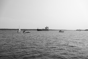 A large tanker boat on the river with smaller pleasure boats