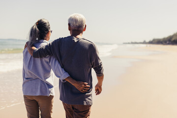 Romantic Senior couple strolling happily along the beach in the sunshine and bright sky. Plan life...