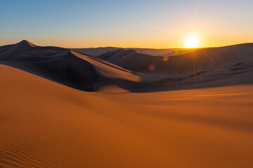 Huacachina desert sunset with lens flare sun star, Peru.