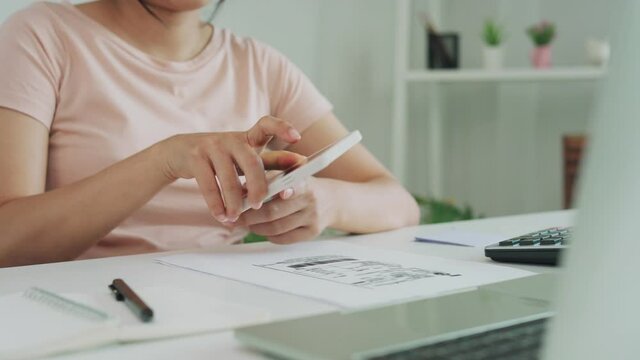 A woman checks documents and scans to pay the invoice. A woman is using a phone scan to verify the details according to the documents. woman paying online.