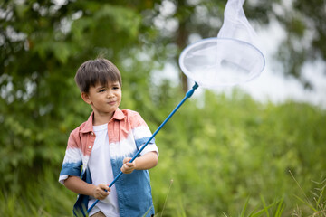 boy with a butterfly net in hand in the green field.