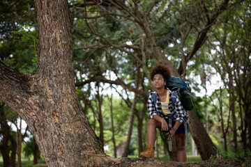  American black female teenager hiking backpacker standing nex to big tree in the forest