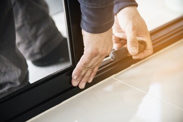 Man doing aluminum frame with wire screen door and window installation work in construction site