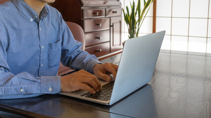 日本のリビング。障子の部屋。ラップトップを操作する男性。