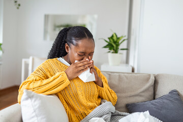 Ill african young woman covered with blanket blowing running nose got fever caught cold sneezing in...
