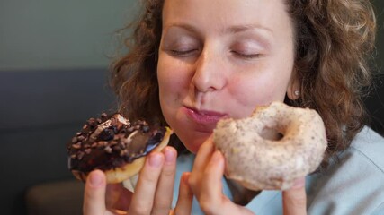 Binge eating concept. Attractive Caucasian woman with eating disorder eating two donuts quickly and at the same time