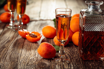 Apricot liquor and fresh apricots on a old wooden table.