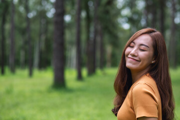 Fototapeta premium Portrait image of a beautiful young asian woman with eyes closed standing in the park