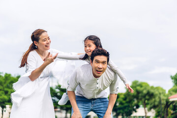 Obraz premium Portrait of enjoy happy love asian family father and mother holding little asian girl on back smiling playing and having fun moments good time in summer park at home