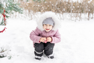 playful little girl with christmas ball by a snowy spruce on a winter day