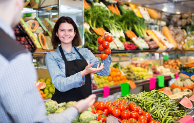Adult woman seller helping customer to buy fruit and vegetables in grocery shop