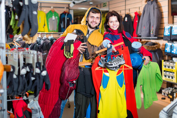 Fototapeta na wymiar Smiling guy and girl show their choice of sports equipment in the store
