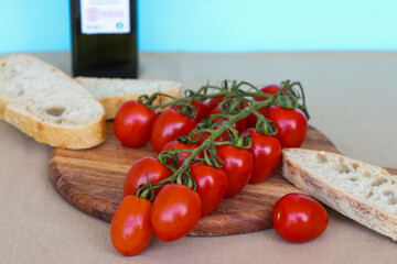 Red cherry tomatoes and slices of white bread on wooden cutting board
