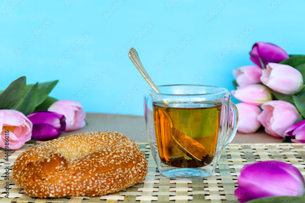 Wall mural spoon in cup of black tea and sesame bagel