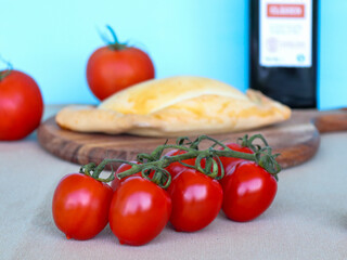 Fresh red tomatoes infront of meat pie on a cutting board