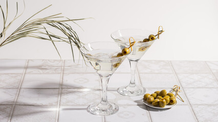 Martini cocktail with olives on a tiled table. Alcoholic classic drink with ice in an elegant glass 
