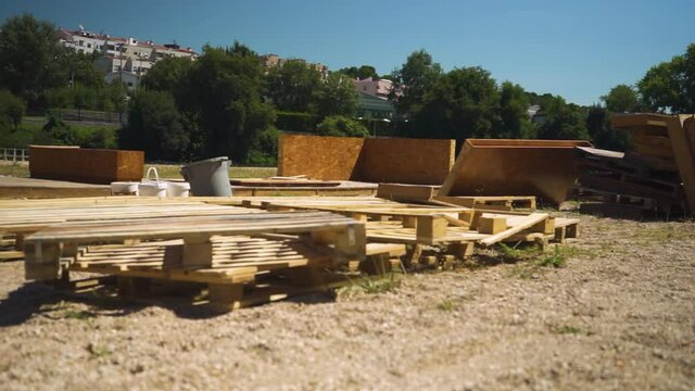 Pallets, wood walls and plastic buckets over sand in a beach river with trees behind