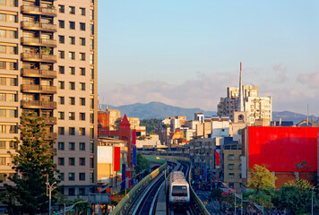 Scenery of a Metro train traveling on the elevated rails of Taipei MRT System by office towers under beautiful sunset sky ~ Cityscape of Taipei, the capital city of Taiwan, on a sunny summer day