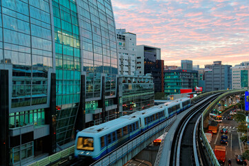 Fototapeta na wymiar Scenery of a train traveling on elevated rails of Taipei Metro (MRT System ) under dramatic sunset sky with golden clouds reflected on the glass curtain walls of a modern office block in Neihu, Taipei