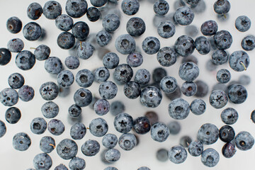 Fresh ripe blueberries flying in the air on a light background. Food levitation concept. Healthy food, ripe fruits, berries. Copy space