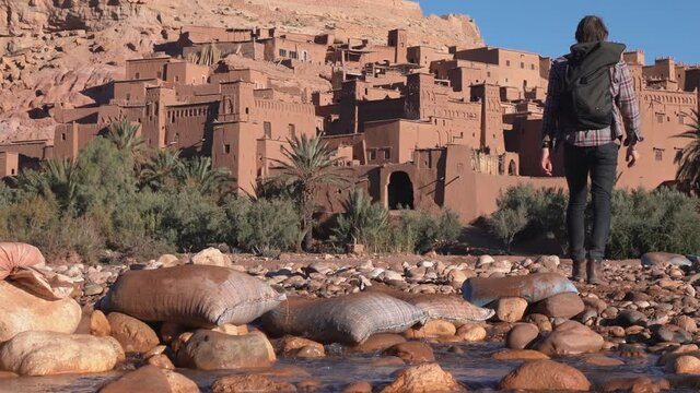Ait Ben Haddoud palm trees in the desert, a Man Crosses a Stream on Stepping Stones