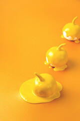 Three yellow Halloween pumpkins with liquid paint flowing. Minimal Holiday season concept orange background. Copy space