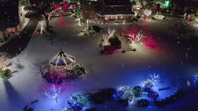 Snowflakes and winter snow in Christmas light display. Beautiful home and estate property decorations at night.