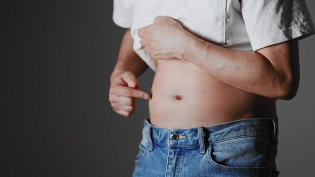 お腹のぜい肉を触る男性　ダイエットイメージ